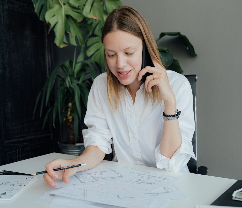 Professional woman providing remote HR support over the phone while reviewing documents at her desk