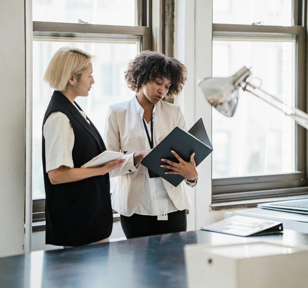 Two HR consultants discussing employee policies and strategies in a bright modern office.