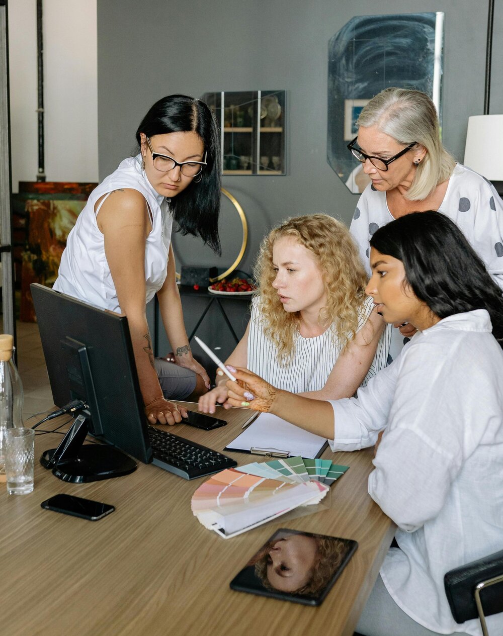 Diverse team of professionals collaborating at a desk, reviewing documents and policies on a computer in a modern office.